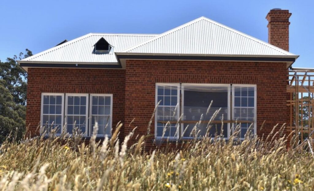 Red Brick House with Arched Window and Grassy Surroundings
